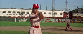 Movie still from “A League of Their Own” (1992), directed by Penny Marshall – A woman in a baseball uniform holding a baseball bat on a baseball field; Medium shot, Low angle