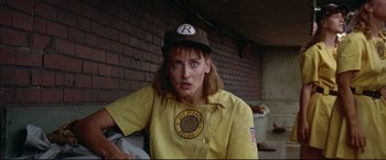 Movie still from “A League of Their Own” (1992), directed by Penny Marshall – A woman in a baseball uniform is standing in front of a brick wall; Close Up shot, Low angle