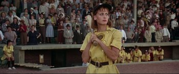 Movie still from “A League of Their Own” (1992), directed by Penny Marshall – A woman holding a baseball bat while standing in front of a crowd of people; Medium shot, Low angle