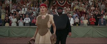Movie still from “A League of Their Own” (1992), directed by Penny Marshall – A woman in a catcher's outfit and a man in a catcher's uniform stand in front of a crowd; Medium shot, Over the shoulder angle