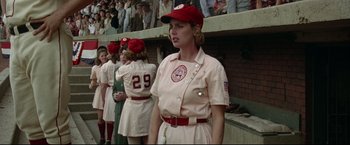 Movie still from “A League of Their Own” (1992), directed by Penny Marshall – A woman in a baseball uniform standing in front of a group of people; Medium shot, Low angle