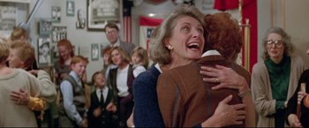 Movie still from “A League of Their Own” (1992), directed by Penny Marshall – An older woman holding a teddy bear in front of a group of people; Medium shot, Over the shoulder angle