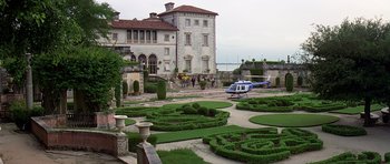 Movie still from “Airport '77” (1977), directed by Jerry Jameson – People are walking around a garden with a helicopter in the foreground; Extreme Wide shot, High angle