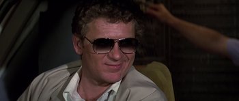 Movie still from “Airport '77” (1977), directed by Jerry Jameson – A person wearing a suit and sunglasses; Close Up shot, Low angle
