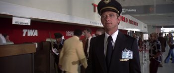 Movie still from “Airport '77” (1977), directed by Jerry Jameson – A man in a suit and tie wearing a hat; Medium shot, Low angle