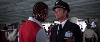 Movie still from “Airport '77” (1977), directed by Jerry Jameson – A man in a uniform talking to another man in an airport; Close Up shot, Over the shoulder angle