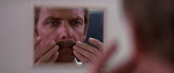 Movie still from “Airport '77” (1977), directed by Jerry Jameson – A person with a mustache looking in a mirror; Close Up shot, Over the shoulder angle