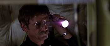 Movie still from “Airport '77” (1977), directed by Jerry Jameson – A man holding a flashlight up to his head; Close Up shot, Low angle