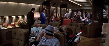 Movie still from “Airport '77” (1977), directed by Jerry Jameson – A group of people sitting in chairs in a room; Wide shot, High angle