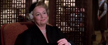 Movie still from “Airport '77” (1977), directed by Jerry Jameson – An older woman wearing a hat and a black jacket; Close Up shot, Over the shoulder angle