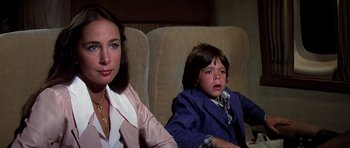 Movie still from “Airport '77” (1977), directed by Jerry Jameson – A woman sitting next to a child on a couch; Close Up shot, High angle
