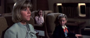 Movie still from “Airport '77” (1977), directed by Jerry Jameson – A woman and two girls sitting in a room; Medium shot, Over the shoulder angle