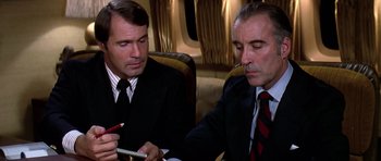 Movie still from “Airport '77” (1977), directed by Jerry Jameson – Two men in suits and ties sitting next to each other; Close Up shot, High angle