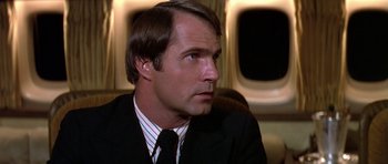 Movie still from “Airport '77” (1977), directed by Jerry Jameson – A person wearing a suit and tie; Close Up shot, Low angle