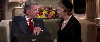 Movie still from “Airport '77” (1977), directed by Jerry Jameson – An older man and a younger woman are talking to each other; Medium shot, Over the shoulder angle