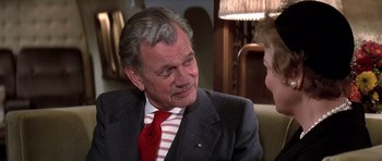 Movie still from “Airport '77” (1977), directed by Jerry Jameson – An older man wearing a suit and red tie; Close Up shot, Over the shoulder angle