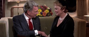 Movie still from “Airport '77” (1977), directed by Jerry Jameson – An older man and a younger woman shaking hands; Close Up shot, High angle