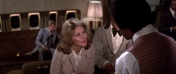 Movie still from “Airport '77” (1977), directed by Jerry Jameson – A woman sitting next to a man in a room; Close Up shot, Over the shoulder angle