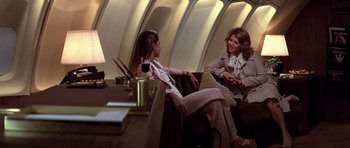 Movie still from “Airport '77” (1977), directed by Jerry Jameson – Two women sitting on a couch on a plane; Medium shot, Over the shoulder angle