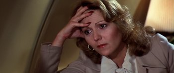 Movie still from “Airport '77” (1977), directed by Jerry Jameson – A person holding her head; Close Up shot, High angle