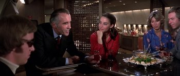 Movie still from “Airport '77” (1977), directed by Jerry Jameson – A man and a woman sitting at a table with drinks; Medium shot, Over the shoulder angle