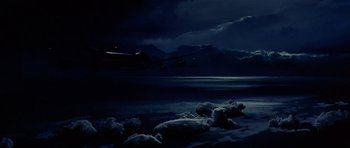 Movie still from “Airport '77” (1977), directed by Jerry Jameson – An airplane flying over a body of water at night; Extreme Wide shot, Low angle