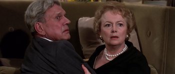 Movie still from “Airport '77” (1977), directed by Jerry Jameson – An older man and a younger woman sitting on a couch; Close Up shot, Over the shoulder angle