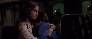 Movie still from “Airport '77” (1977), directed by Jerry Jameson – A young woman holding a young boy while sitting in a car; Close Up shot, Over the shoulder angle