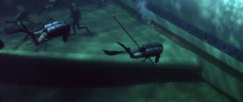 Movie still from “Airport '77” (1977), directed by Jerry Jameson – A scuba diver in the water with other scuba divers in the background; Wide shot, High angle