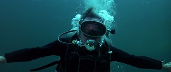 Movie still from “Airport '77” (1977), directed by Jerry Jameson – A man in a wetsuit and a mask is underwater; Medium shot, Overhead angle