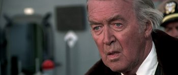 Movie still from “Airport '77” (1977), directed by Jerry Jameson – An older man with a serious look on his face; Close Up shot, Over the shoulder angle