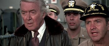Movie still from “Airport '77” (1977), directed by Jerry Jameson – A man in a suit and tie standing next to another man in a uniform; Close Up shot, Over the shoulder angle