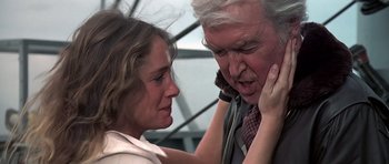 Movie still from “Airport '77” (1977), directed by Jerry Jameson – An older man talking on a phone while a younger woman looks on; Close Up shot, Over the shoulder angle