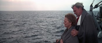 Movie still from “Airport '77” (1977), directed by Jerry Jameson – A woman wrapped in a blanket standing next to a man in the ocean; Medium shot, High angle