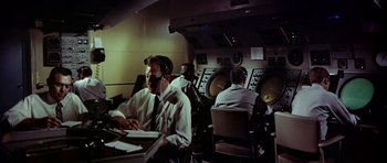 Movie still from “Airport” (1970), directed by George Seaton – A group of men sitting at a table in front of a computer; Medium shot, High angle