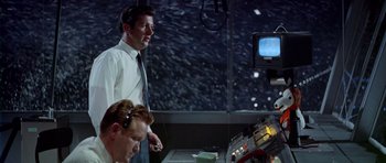 Movie still from “Airport” (1970), directed by George Seaton – Two men are in a control room and one of them is holding a remote control; Medium shot, Low angle