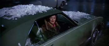 Movie still from “Airport” (1970), directed by George Seaton – A woman sitting in the passenger seat of a green car; Medium shot, High angle