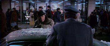 Movie still from “Airport” (1970), directed by George Seaton – A man in a black hat and a man in a gray suit and black hat; Medium shot, Over the shoulder angle