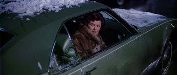Movie still from “Airport” (1970), directed by George Seaton – A woman sitting in the drivers seat of a green car; Medium shot, High angle