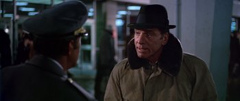Movie still from “Airport” (1970), directed by George Seaton – A man wearing a hat and a jacket talking to another man; Close Up shot, Over the shoulder angle