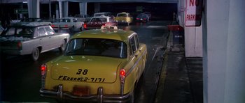 Movie still from “Airport” (1970), directed by George Seaton – A yellow taxi driving down a street at night; Wide shot, Low angle