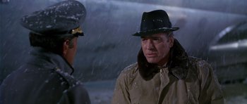 Movie still from “Airport” (1970), directed by George Seaton – A man wearing a hat and a jacket talking to another man in the snow; Close Up shot, Over the shoulder angle