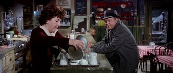 Movie still from “Airport” (1970), directed by George Seaton – An older man and a woman are washing dishes in a sink; Medium shot, Over the shoulder angle