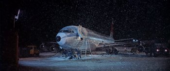 Movie still from “Airport” (1970), directed by George Seaton – An airplane is being worked on in the snow; Extreme Wide shot, High angle