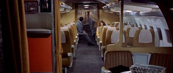 Movie still from “Airport” (1970), directed by George Seaton – A man and a woman sitting in a train car; Wide shot, High angle