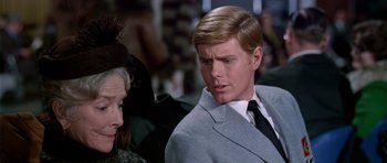Movie still from “Airport” (1970), directed by George Seaton – A man in a suit and tie next to an older woman; Close Up shot, Over the shoulder angle