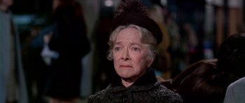 Movie still from “Airport” (1970), directed by George Seaton – An older woman wearing a black hat and a black coat; Close Up shot, Over the shoulder angle