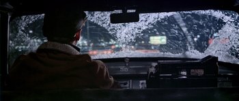 Movie still from “Airport” (1970), directed by George Seaton – A man sitting in the drivers seat of a car looking out the window; Medium shot, Over the shoulder angle