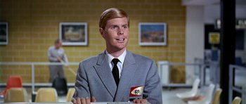 Movie still from “Airport” (1970), directed by George Seaton – A man wearing a suit and tie holding a flag; Close Up shot, Low angle
