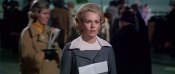 Movie still from “Airport” (1970), directed by George Seaton – A woman in a gray coat and white shirt; Close Up shot, Low angle